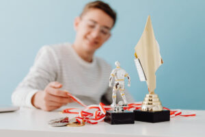 A collection of awards on a table, including a trophy, a miniature sports figure, and several medals with red and white ribbons.