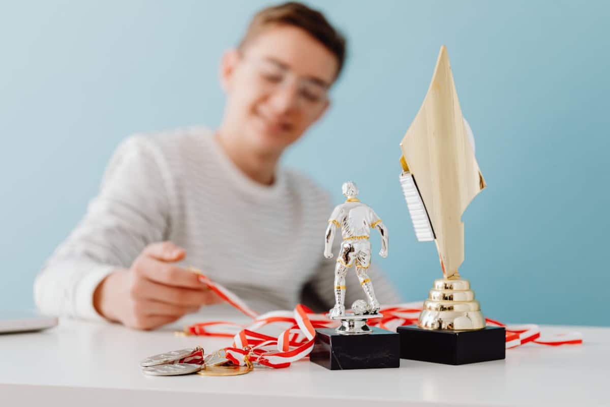 A collection of awards on a table, including a trophy, a miniature sports figure, and several medals with red and white ribbons.