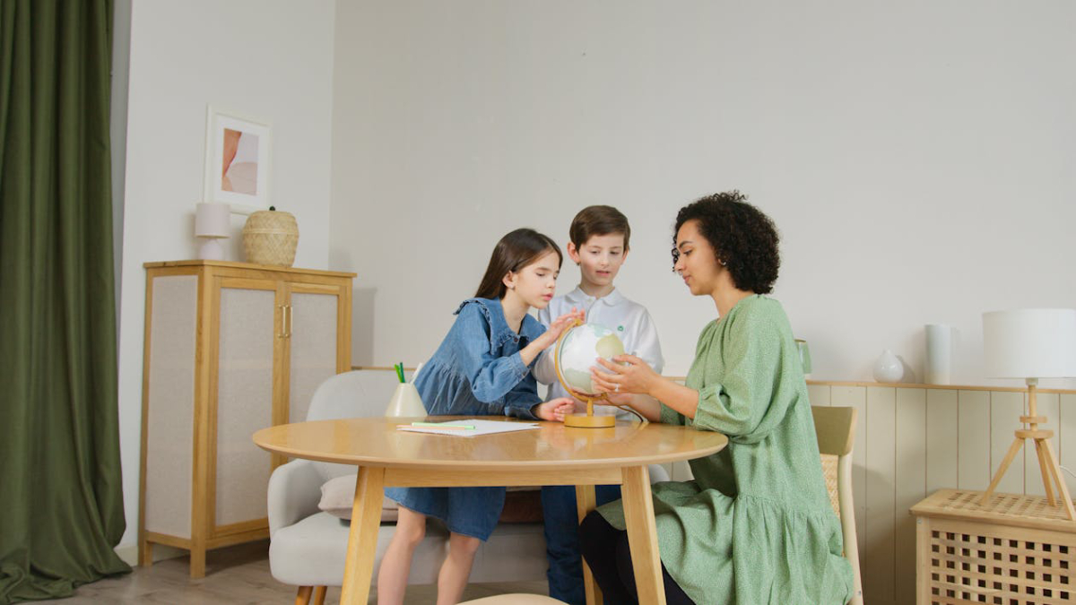 A child and an adult examine a globe together at a round table in a modern, light-filled room with minimalist decor.