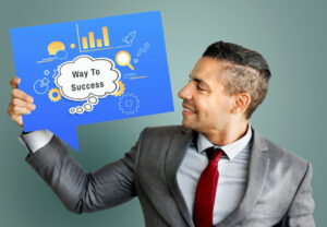 A business professional in a suit holds a speech bubble sign that reads Way To Success.