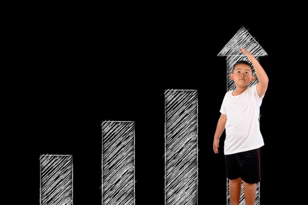 A child in a white shirt stands beside a sketched bar graph, reaching towards an upward arrow symbolizing growth.