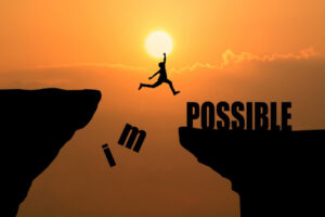 A silhouette of a person jumping between cliffs at sunset, with the phrase I'm possible.