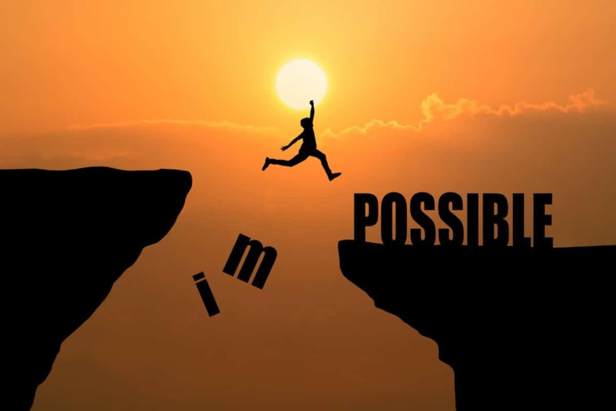 A silhouette of a person jumping between cliffs at sunset, with the phrase I'm possible.