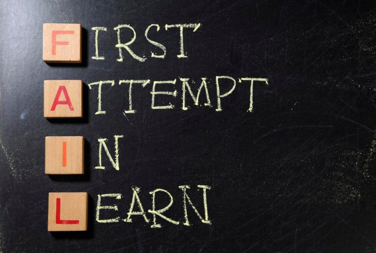 Wooden blocks spelling FAIL on a chalkboard with the phrase First Attempt In Learning written around them.